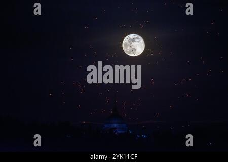 Der Vollmond erhebt sich hinter dem Buddha’s Footprint von Yonok City, begleitet von schwimmenden Lannas-Laternen am Loy Krathong Day im Wat Phra That Doi Saket. Stockfoto