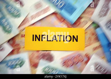 Inflation. Ein gelbes Stück Papier mit dem Wort Inflation auf einem Haufen russischer Rubel-Banknoten. Bewegungsunschärfe. Nahaufnahme. Stockfoto