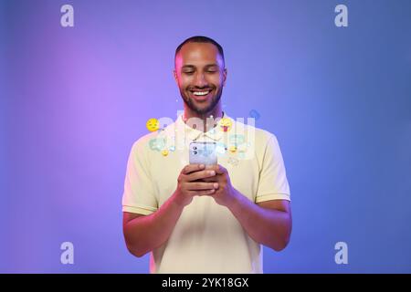 Glücklicher Mann mit Handy auf farbigem Hintergrund. Neues Nachrichtenzeichen und andere Benachrichtigungen über Gadget Stockfoto