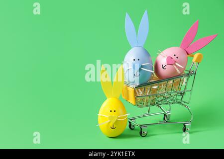 Warenkorb voller Ostereier, auf grünem Hintergrund, Kopierraum. Verkaufskonzept Stockfoto