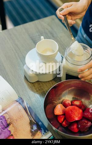 Zucker auf digitaler Küchenwaage mit Kekszutaten zum Backen auf Holztisch. Hochwertige Fotos Stockfoto