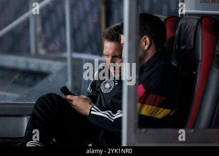 Freiburg Im Breisgau, Deutschland. November 2024. Julian Nagelsmann (Trainer Deutschland) und Benjamin GL?ck (Assistenztrainer Deutschland) schauen auf GL?cks Smartphone UEFA Nations League: Deutschland - Bosnien Herzegowina; Freiburg im Breisgau, Europa-Park-Stadion am 16.11.2024 Credit: dpa/Alamy Live News Stockfoto