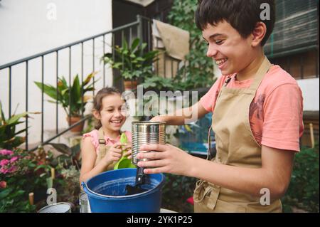 Zwei glückliche Kinder genießen es, im Garten zu Pflanzen, um Teamarbeit und Naturverbundenheit zu fördern. Ihr Lächeln spiegelt die Freude an Outdoor-Aktivitäten wider Stockfoto