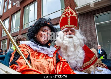 Nikolaus und einer seiner Helfer posieren für die Kamera. Am ersten Samstag nach dem 11. November trifft die rot-weiß-bekleidete Sinterklaas (St. Nikolaus) in mehreren niederländischen Städten ein. In Nijmegen ging Sinterklaas auf einer Route durch das Stadtzentrum, begleitet von seinen Helfern, dem Pieten (Peters), der Kindern und Erwachsenen traditionelle Süßigkeiten schenkte. Stockfoto