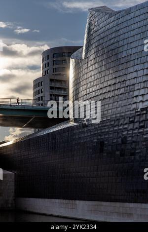 Jogger auf der Brücke vor dem Guggenheim Museum, Bilbao. Sonnenlicht auf der Fassade. Baskenland, Spanien Stockfoto