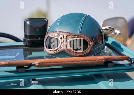 Blaugrüner Oldtimer-Helm und Brille an einem alten Auto Stockfoto