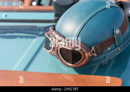 Blaugrüner Oldtimer-Helm und Brille an einem alten Auto Stockfoto
