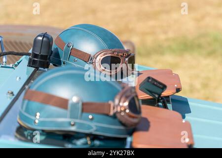 Blaugrüner Oldtimer-Helm und Brille an einem alten Auto Stockfoto