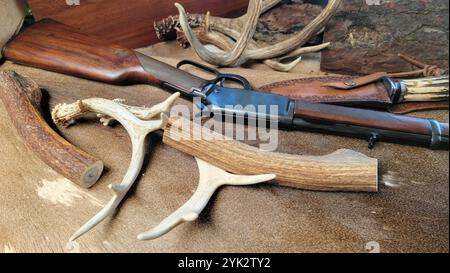 Blick auf ein Hebelgewehr mit Hirschgeweih und Jagdmesser auf Hirschhaut Stockfoto