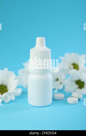 Allergiebehandlung. Nasentropfen, Pillen und Blumen auf hellblauem Hintergrund, Nahaufnahme Stockfoto