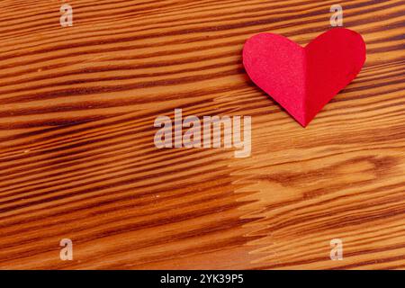 Handgeschnittenes Herz aus rotem Papier auf hölzernem Hintergrund hochwertiges Foto. Stockfoto