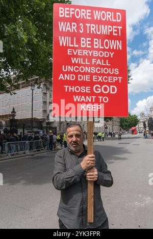 London, Großbritannien. Juni 2017. Nachdem die Wahlergebnisse zeigten, dass keine Partei eine Mehrheit hatte, kamen Demonstranten nach Westminster, um Theresa May zurückzutreten. Sie will bleiben und versuchen, zu regieren, indem sie sich auf Stimmen der protestantischen extremistischen DUP-Partei Ulster stützt, die mit loyalistischen Paramilitärs in Verbindung steht. Ein Demonstrant in der Downing Street hält ein großes doppelseitiges Plakat über die Gefahren des 3. Weltkriegs, das alle töten wird, außer 'die, die GOTT behalten will'. Stockfoto