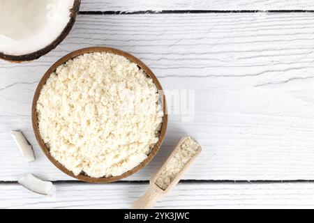 Kokosmehl in einer Holzschüssel und frische Kokosnüsse auf weißem hölzernem Hintergrund. Backzutaten. Glutenfreie Speisen Stockfoto