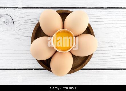 Rohe Eier in einer Holzschale auf weißem Hintergrund. Draufsicht. Kuchen- oder Kuchenrezept. Draufsicht. Stockfoto