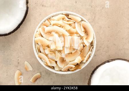 Kokos-Chips oder Kokosflocken und frische halbe Kokosnüsse auf beigem Hintergrund. Draufsicht. Gesunde Snacks. Kokos-Dessert. Stockfoto