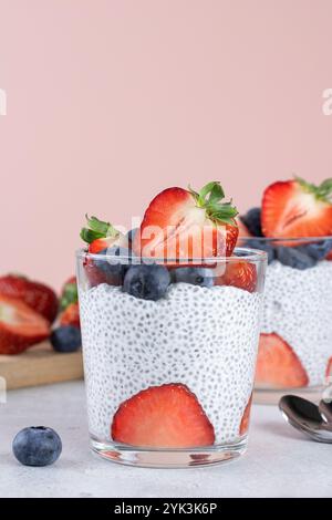 Chia Pudding mit Erdbeeren und Heidelbeeren, Chiasamen auf rosa Hintergrund. Gesundes Frühstückskonzept. Kopierbereich. Stockfoto