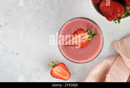 Erdbeeren-Smoothie oder Cocktail mit Beeren auf grauem Hintergrund. Sommergetränke. Draufsicht. Kopierbereich. Stockfoto