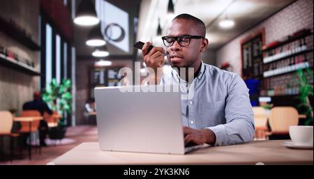 Mann Trinkt Kaffee Und Arbeitet Am Laptop. Sprachnachricht Auf Dem Telefon Senden Stockfoto