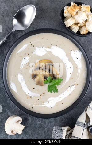 Pilzcremesuppe mit Croutons auf einem schwarzen Teller auf grauem Hintergrund. Draufsicht. Stockfoto