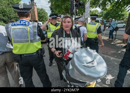 Maidenhead, Großbritannien. Juni 2017. Die Polizei umgibt Menschen mit Behinderungen gegen Schnitte Demonstranten, die eine Hauptstraße in die Stadt blockieren, um im Wahlkreis Theresa May&#8217 gegen die Tory-Regierung zu protestieren, die weltweit die erste Regierung, die der schweren und systematischen Menschenrechtsverletzungen von Behinderten durch die UNO für schuldig befunden wurde, und sagt ihnen, dass sie von der Straße gehen müssen. Ein Polizist folgt Paula Peters, während sie sich bewegt, um eine Störung zu vermeiden. Die Kürzungen, die sie seit 2010 vorgenommen haben, hatten neunmal so viele Auswirkungen auf Behinderte wie auf jede andere Gruppe, 19 Mal mehr für Menschen mit hohem Gewicht Stockfoto