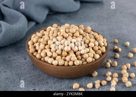 Rohe Kichererbsen in Holzschüssel auf blauem Hintergrund. Superfood. Stockfoto