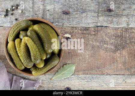 Eingelegte Gurken in einer Holzschale mit Gewürzen auf hölzernem Hintergrund. Marinierte eingelegte Gurken. Draufsicht. Kopierbereich. Stockfoto