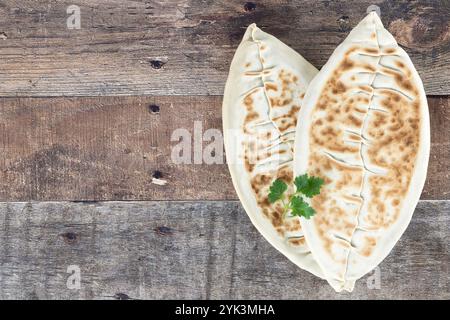 Qutab, kutab mit Grün auf hölzernem Hintergrund. Aserbaidschanisches Fladenbrot mit Gemüse. Draufsicht, Kopierraum. Stockfoto