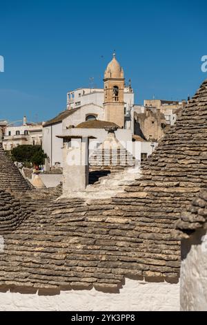 Trulli Häuser mit der Kirche Santa Lucia im Hintergrund in Alberobello, Apulien, Italien. Stockfoto