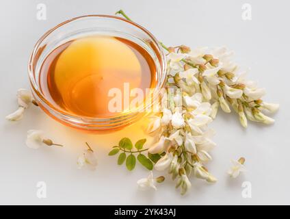 Natürlicher Bio-Honig in Glasschale, Honigpflanzen Akazienblüten und Blätter in der Nähe. Topv-Ansicht. Stockfoto