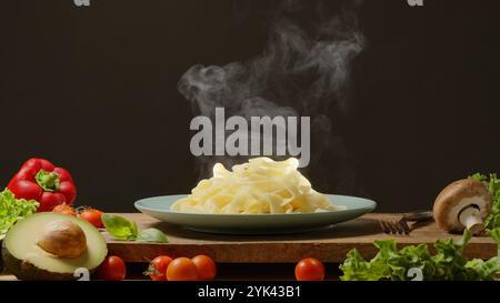 Heiße, dampfende, frisch zubereitete Pasta und frisches Gemüse in der Nähe, Pasta ist mediterrane italienische traditionelle Küche. Stockfoto