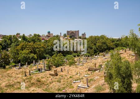 Samarkand, Usbekistan - 6. Juli 2024: Blick auf das Bibi-Khanym Mausoleum im Hintergrund und im Vordergrund auf einen Erdfriedhof Stockfoto