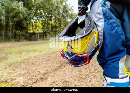 Nahaufnahme des Motocross-Helms, der vom Fahrer gehalten wird, zeigt Geländeabenteuer, Schutzausrüstung und die Spannung des Motocross-Sports und der Sicherheit. Stockfoto