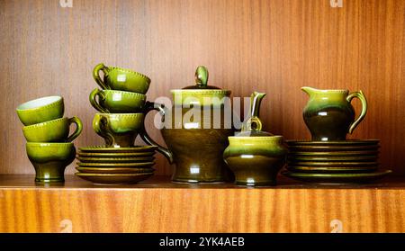 Altes Vintage-Glas-Teekaffee-Set. Retro-Töpferkeramik setzt herbstgrüne Farben, die Tageslicht auf hölzernem Hintergrund leuchten Stockfoto