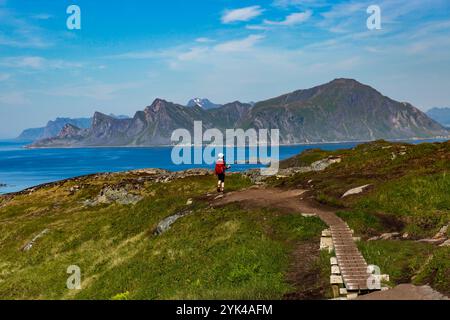 Ein junges Mädchen wandert auf einem malerischen Wanderweg in Lofoten, Norwegen, umgeben von der zerklüfteten Schönheit der Berge und Fjorde Stockfoto