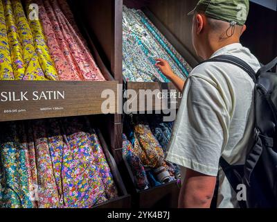 London, England, chinesischer Tourist, Einkaufsbummel im Inneren, altes Geschäft, 'Liberty', traditionelles englisches Kaufhaus, Seidenstoffe auf der Ausstellung Stockfoto