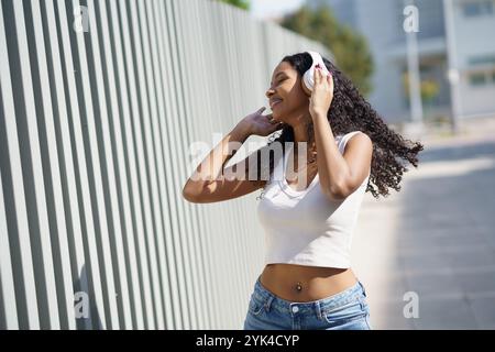 Eine freudige junge Frau, die Musik genießt und hört, während sie draußen in der Natur ist Stockfoto