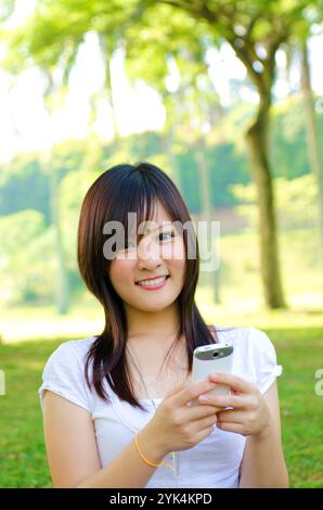 SMS glücklicher orientalischer junger Student mit Handy online / sms / Outdoor Green Park Copyright: xZoonar.com/szefeix 1053981987 Stockfoto