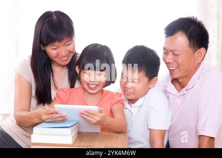 Eltern und Kinder verwenden gemeinsam einen Tablet-pc. Asiatische Familie zu Hause. Eltern und Kinder nutzen gemeinsam einen digitalen Tablet-Computer. Copyright: XZoonar.c Stockfoto