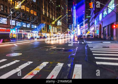 Blick auf die Straße bei Nacht in Manhattan, New York City, mit farbenfrohen Neonlichtern, verschwommenen Pfaden und lebendiger urbaner Energie. New York. USA. Stockfoto