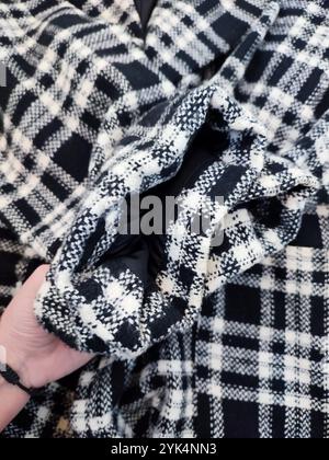 Mantelmanschetten nah oben, schwarz weiß karierter karierter Mantel, Stoff, Textil, Kleidungsdetails, flach auf weißem Marmorhintergrund Stockfoto
