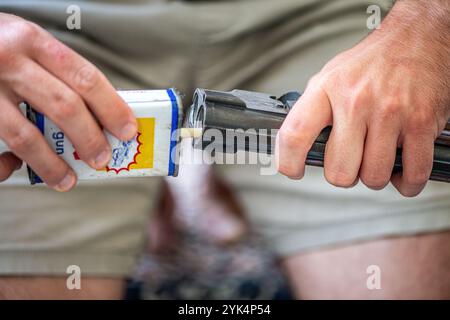 Ein Mann reinigt ein altes Gewehr sorgfältig mit Öl und Reinigungsgeräten und zeigt die Liebe zum Detail und die Handwerkskunst alter Schusswaffen. Stockfoto