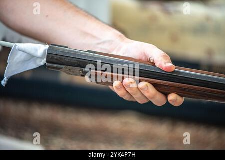 Ein Mann reinigt ein altes Gewehr sorgfältig mit Öl und Reinigungsgeräten und zeigt die Liebe zum Detail und die Handwerkskunst alter Schusswaffen. Stockfoto