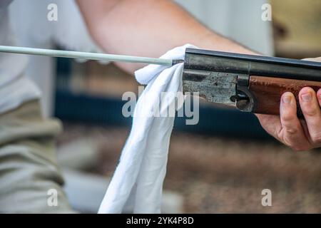 Ein Mann reinigt ein altes Gewehr sorgfältig mit Öl und Reinigungsgeräten und zeigt die Liebe zum Detail und die Handwerkskunst alter Schusswaffen. Stockfoto