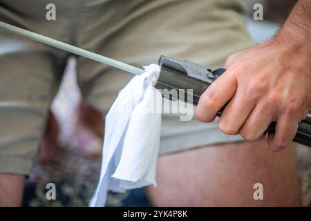 Ein Mann reinigt ein altes Gewehr sorgfältig mit Öl und Reinigungsgeräten und zeigt die Liebe zum Detail und die Handwerkskunst alter Schusswaffen. Stockfoto