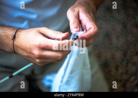 Ein Mann reinigt ein altes Gewehr sorgfältig mit Öl und Reinigungsgeräten und zeigt die Liebe zum Detail und die Handwerkskunst alter Schusswaffen. Stockfoto