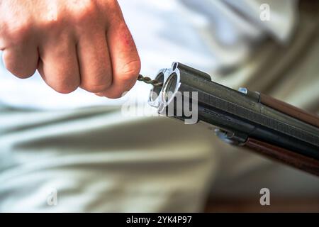 Ein Mann reinigt ein altes Gewehr sorgfältig mit Öl und Reinigungsgeräten und zeigt die Liebe zum Detail und die Handwerkskunst alter Schusswaffen. Stockfoto