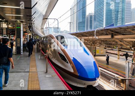 Die Vorderseite eines japanischen Shinkansen-Hochgeschwindigkeitszugs der E7-Serie am Bahnsteig im Bahnhof Tokio. Bahnsteig voll mit Leuten, die darauf warten, in den Zug zu steigen. Stockfoto