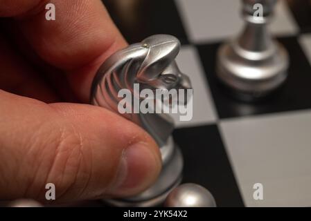 Hand bewegt weißen Ritter auf Schachbrett mit Nahaufnahme Schachspielsteine Stockfoto