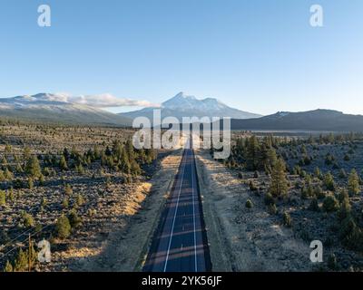 Luftaufnahme der leeren US-Route 97, die bei Sonnenuntergang im nördlichen Kalifornien direkt auf den schneebedeckten Mount Shasta-Vulkan zuführt Stockfoto