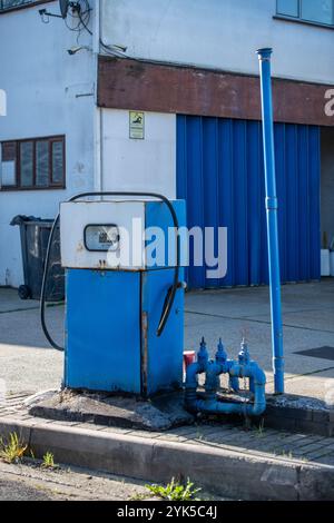 Alte alte Benzinpumpe auf einem verlassenen Vorplatz in einer stillgelegten Garage, alte, nicht funktionierende, veraltete Benzinpumpe auf einem verlassenen Garagenvorplatz. Stockfoto